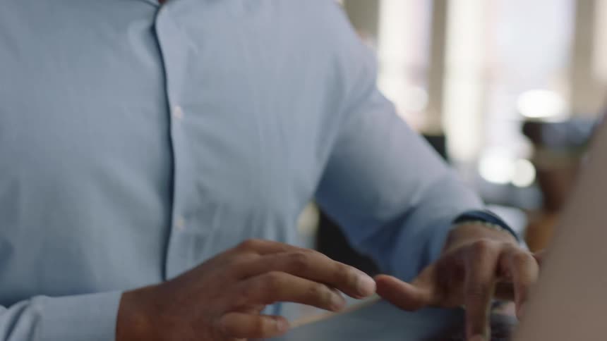 A man sitting at a desk types on a laptop