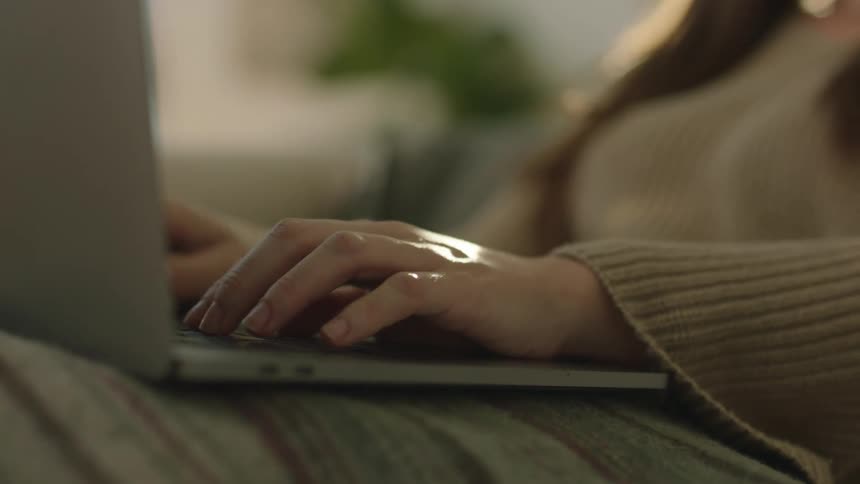 A woman is typing on keyboard working from home