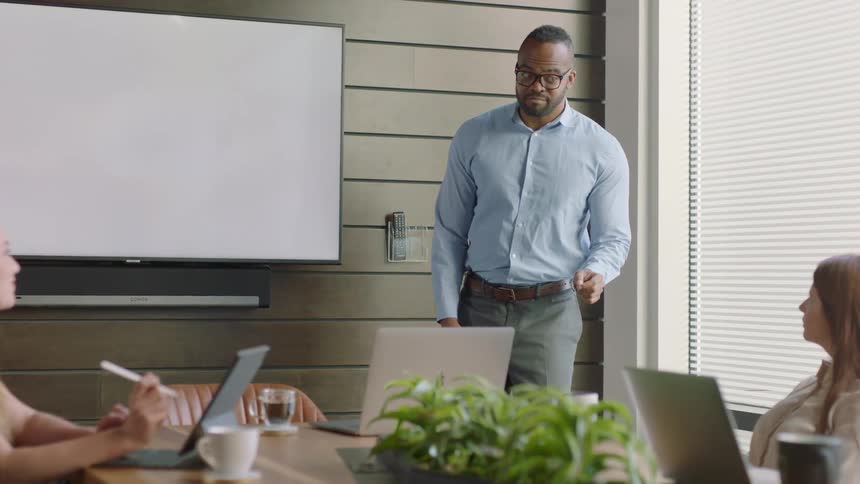 A man is talking with coworkers in the conference room