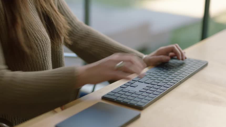A woman sitting at a desk typing on a keyboard working from home