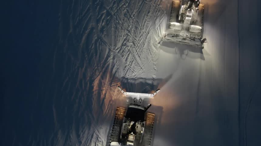 Aerial of snow cats grooming snow at night