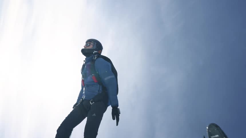 A man is skydiving out of a helicopter above mountains