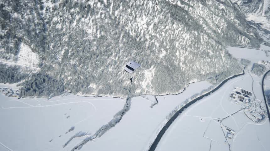 A person hang gliding over snowy areas