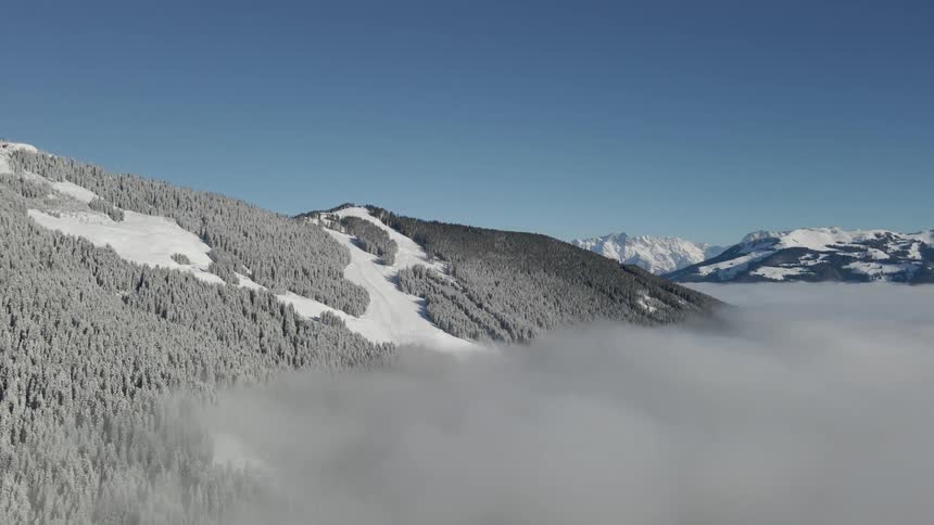 Foggy snow covered forested mountains and a blue sky