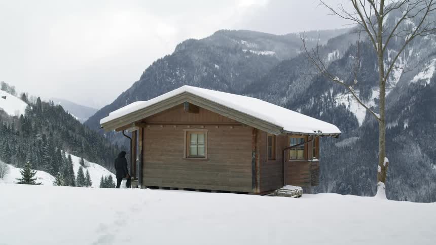 A person is walking towards a wood cabin