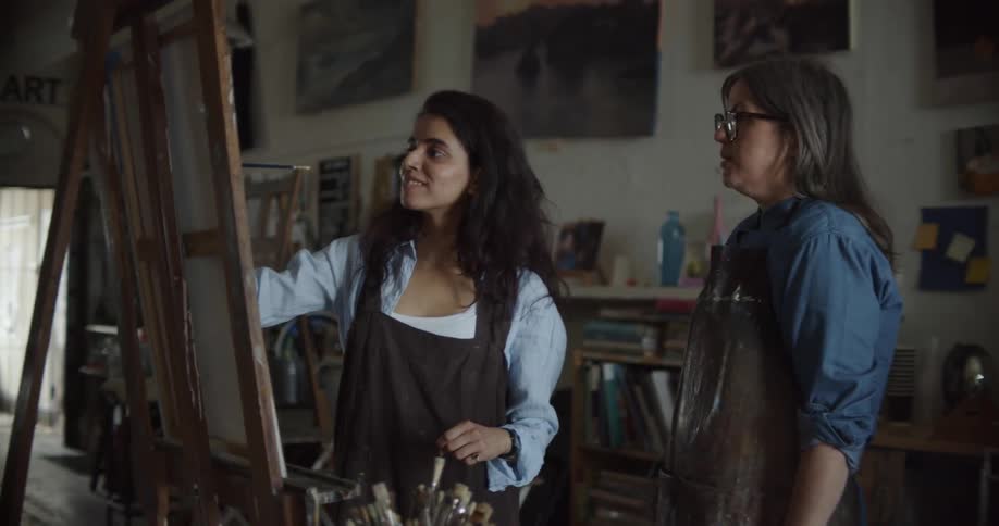 Two women talk as one paints