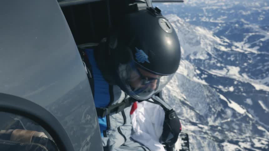 A man staring out of a helicopter getting ready to jump