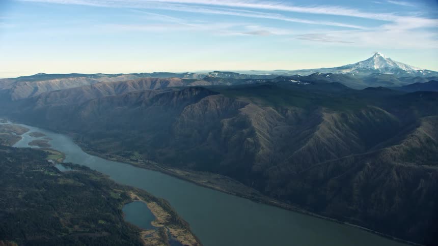 Super wide aerial flying down the Columbia River Gorge with Mount Hood rising high above the Columbia River in the background