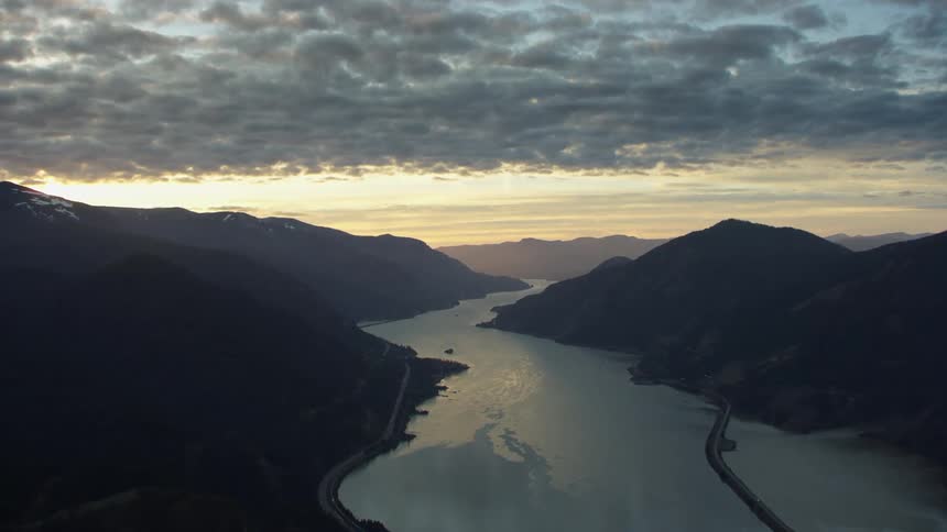 Flying above the Columbia River Gorge and the Columbia River at sunset with beautiful puffy golden light clouds lazily hanging in the sky
