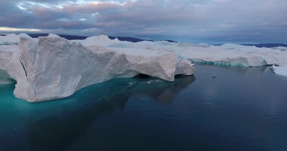 Large ice and snow glaciers sit in dark blue ocean water