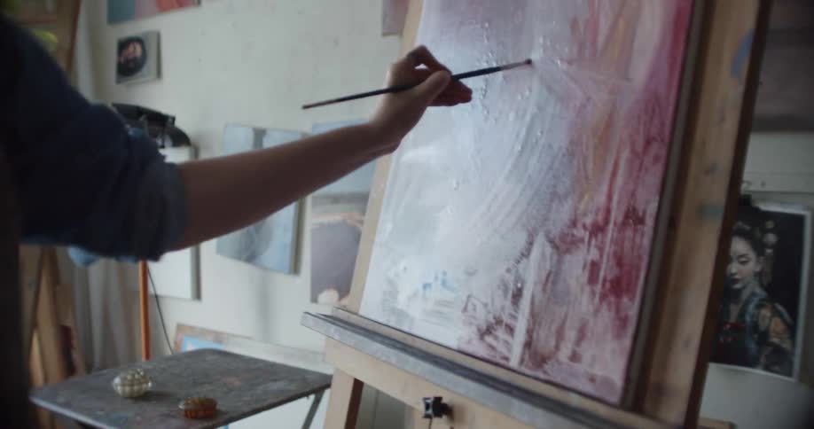 A female artist painting on a canvas in an art studio