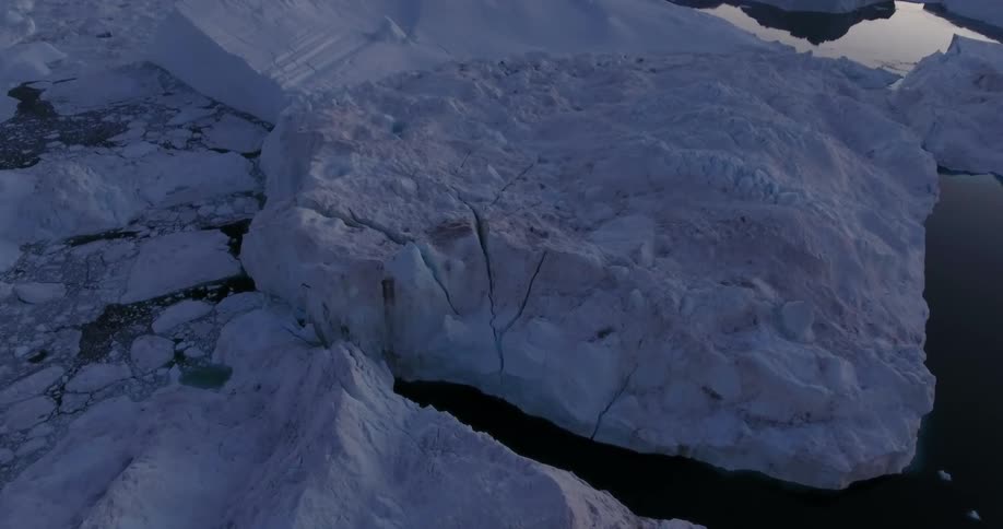 Aerial view of the broken ice surface of a glacier over the ocean at sunset