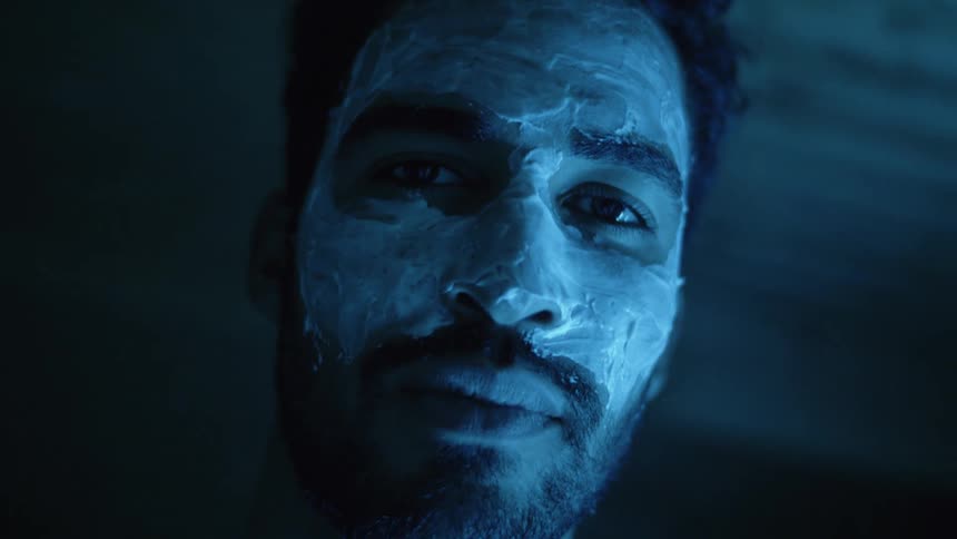 A man in a room staring with cream on his face