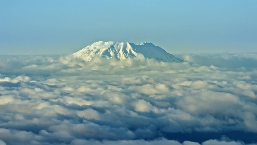Hyper lapse aerial of Mount St Helens rising above a sea of clouds churning and bubbling under the winter sun in this aerial