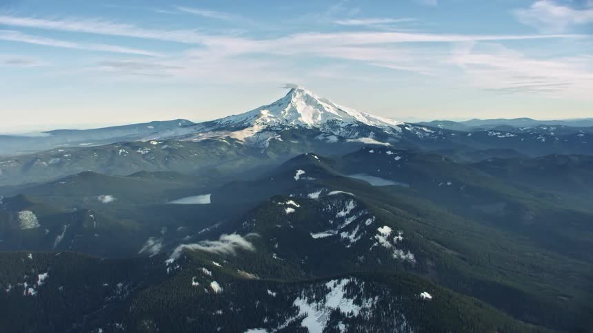 Hyper Lapse flying directly towards Mount Hood in winter as snow blows fiercely off the summit in this middle of winter under a clear blue sky