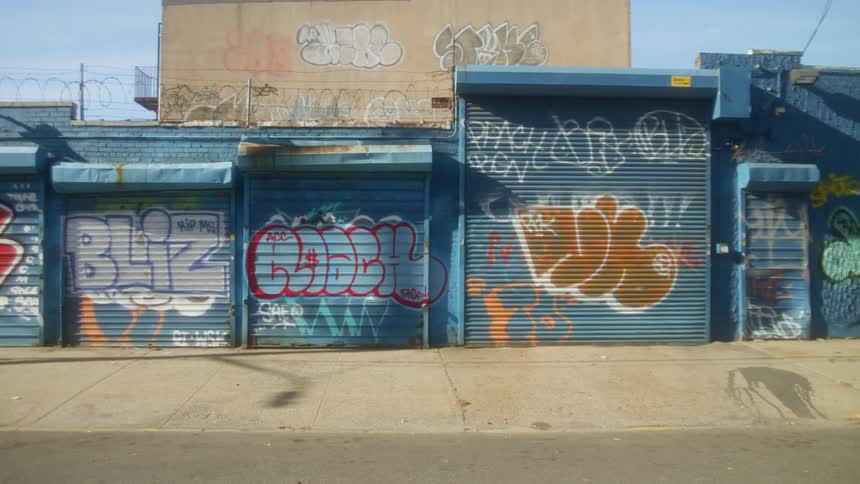 A city street with buildings with graffiti with the sky and clouds in the background