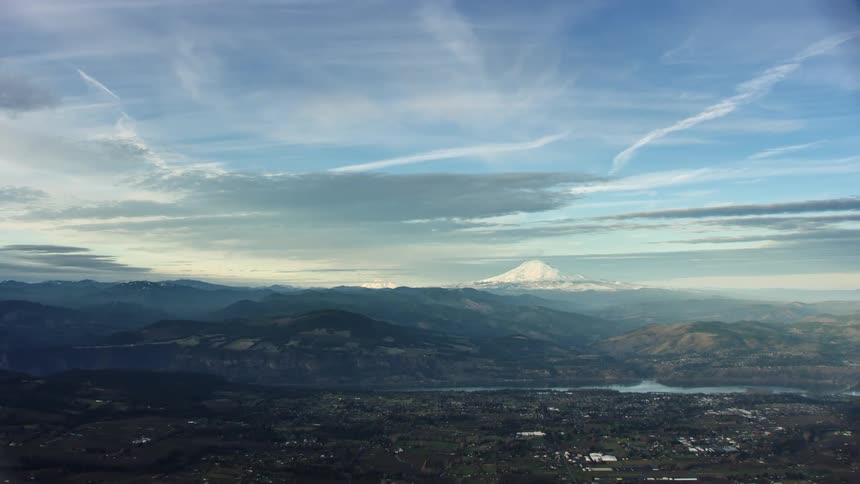 A landscape with buildings and a river with a mountain the sky and clouds in the background