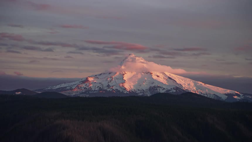 Foreground ridge silhouettes Mount Hood under the glow of sunset as a winter day comes to end