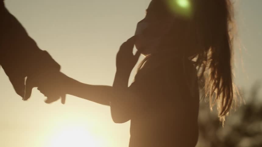 An adult beckons for a girl to talk their hand and the two walk away hand in hand
