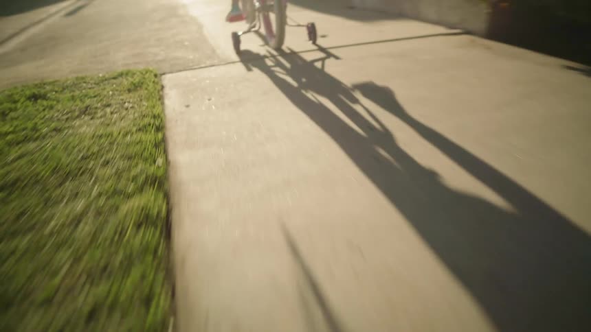 A young child rides their bike on a town sidewalk