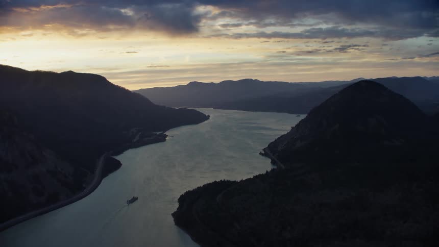 Beautiful wispy sunset clouds illuminate the sky as the camera flies down the Columbia River Gorge after the sun has gone down