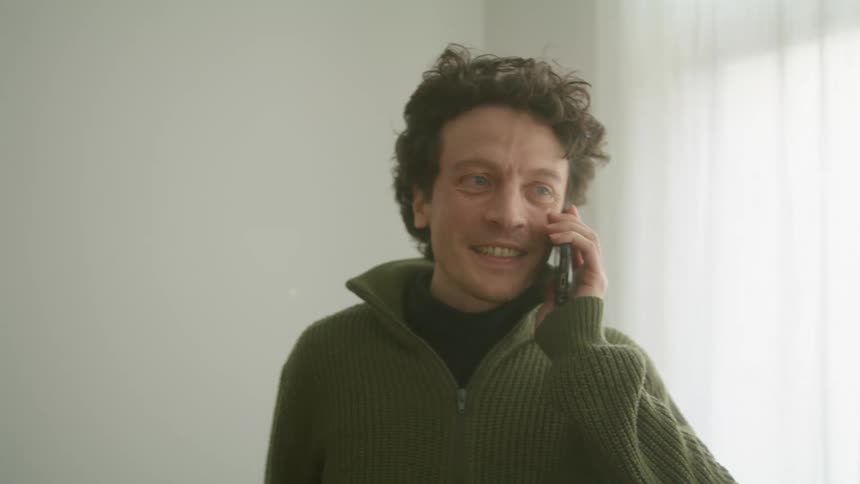 A man talking on a cell phone standing in a room indoors at daytime