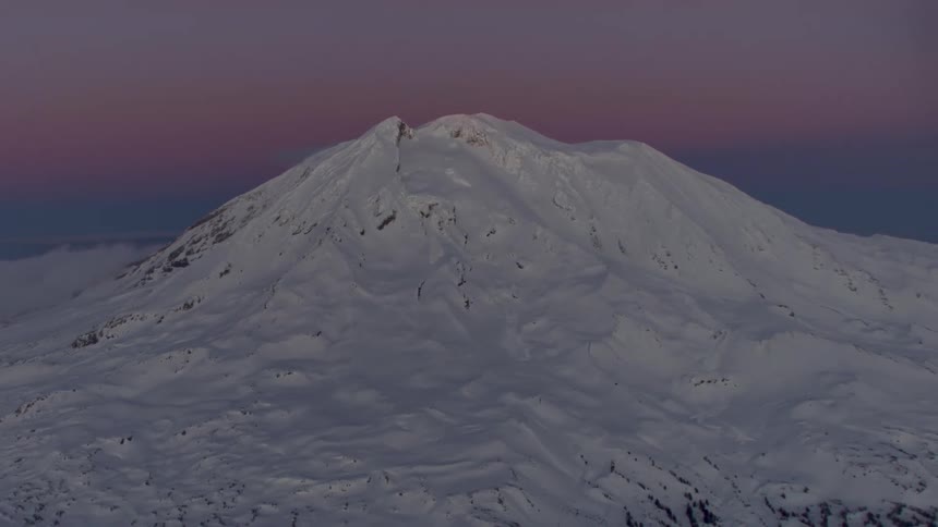 Rotating hyper lapse of a mountain covered in snow and ice deep in the winter with the sunset sky and clouds that eventually darkens into night (Mount Adams)