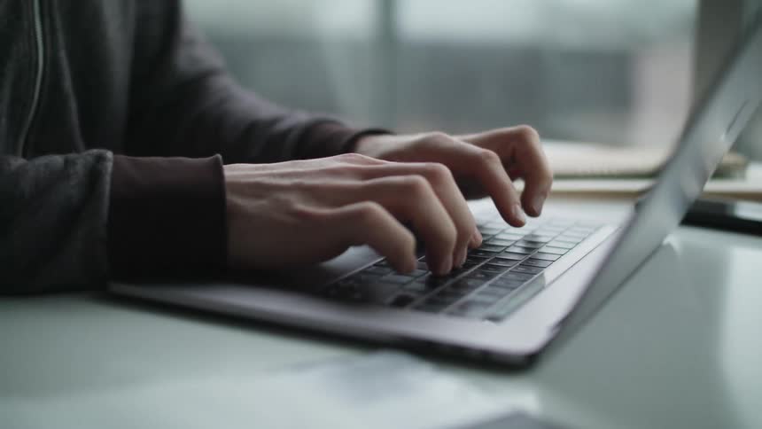 A man in an office types on a laptop