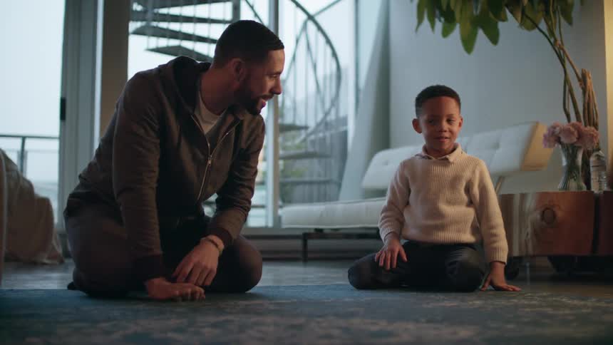 A father and young son playing with toy cars on a living room floor