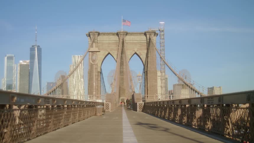 People bicycle across the bridge towards the city on a sunny day