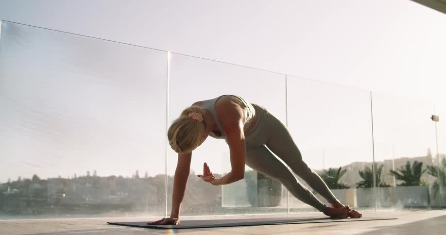 Young fit woman wearing sports clothes working out over a yoga mat at morning
