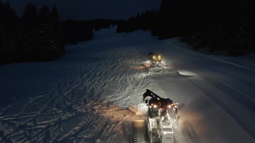 Vehicles are plowing snow off of the streets at night