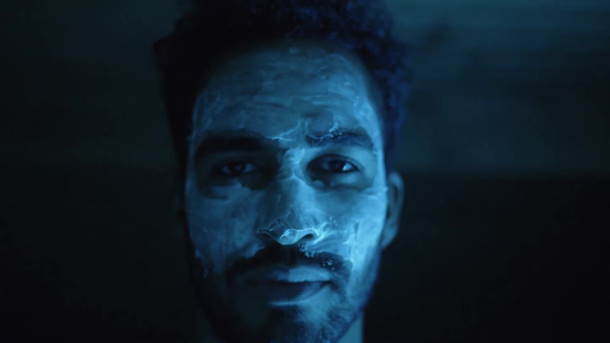 Close up of a young mans face covered in fluorescent fosforescent blue electric paint