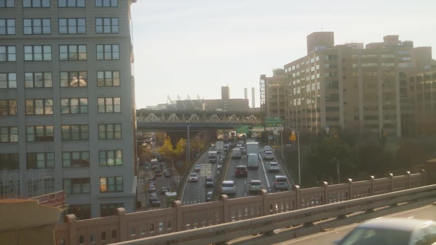 An overpass with vehicles with vehicles buildings a highway trees the sky and clouds in the background