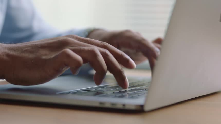 Man wearing typing on laptop in his office