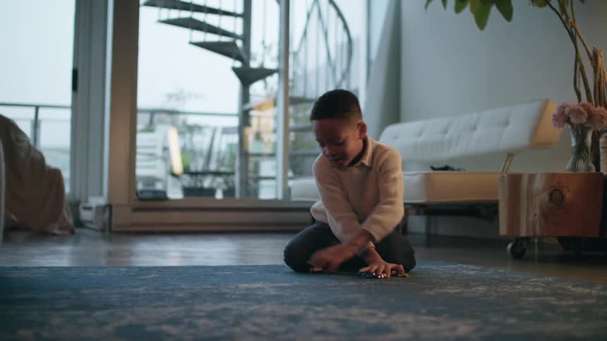 A young boy playing with toy cars on a living room rug