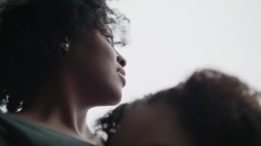 A mother holding her daughter and kissing her on the head