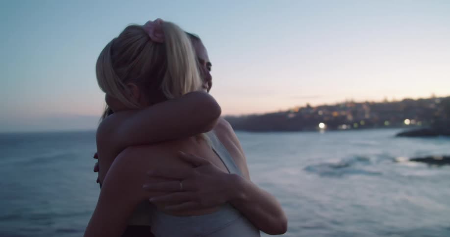 Two women hugging near the ocean