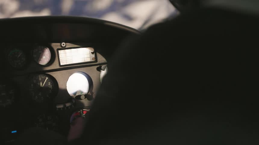 A pilot monitors the instrument panel in the cockpit of a small airplane