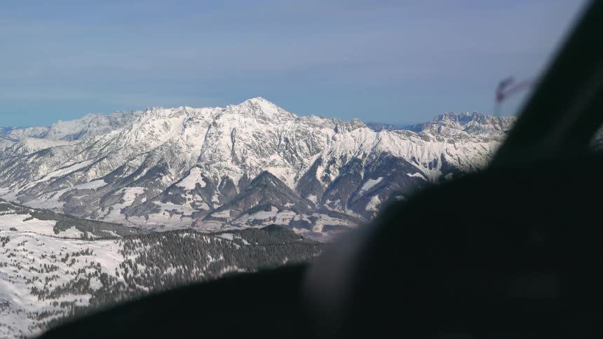 Snow capped mountain ridge through the airplane window on a bright sunny day