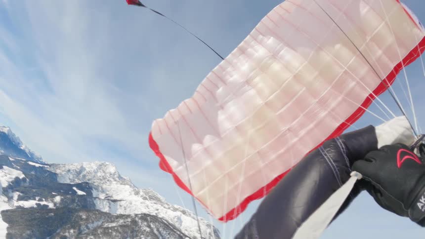 A person paragliding with a mountain range the sky and clouds in the background