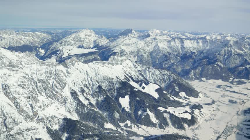 A mountain range covered in ice and snow with the sky and clouds in the background
