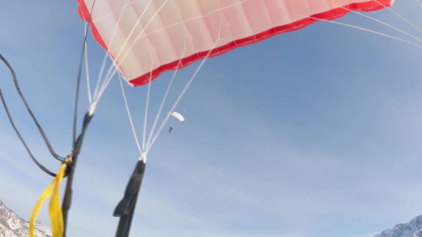 Two people gliding in the sky with parachutes