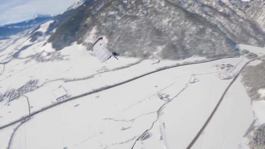 A person paragliding with a mountain range the sky and clouds in the background