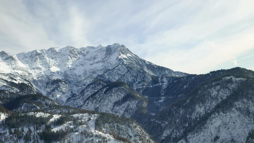 A mountain range covered in snow and ice with the sky and clouds in the background