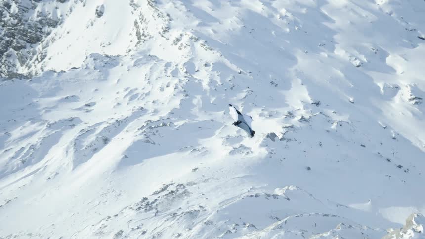 A person is parachuting above a mountain in winter