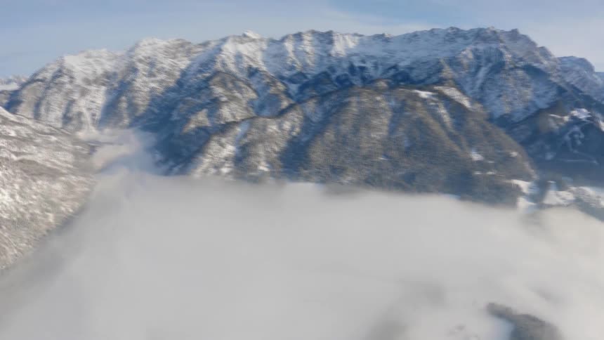 A skydiver holds on tight to a parachute strap as they fly over a mountain range