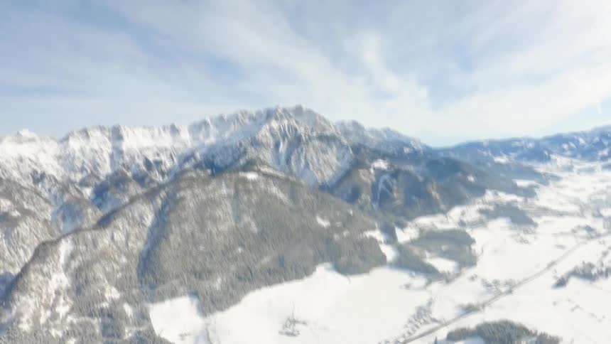 A parachute falling towards snowy mountains in the wilderness