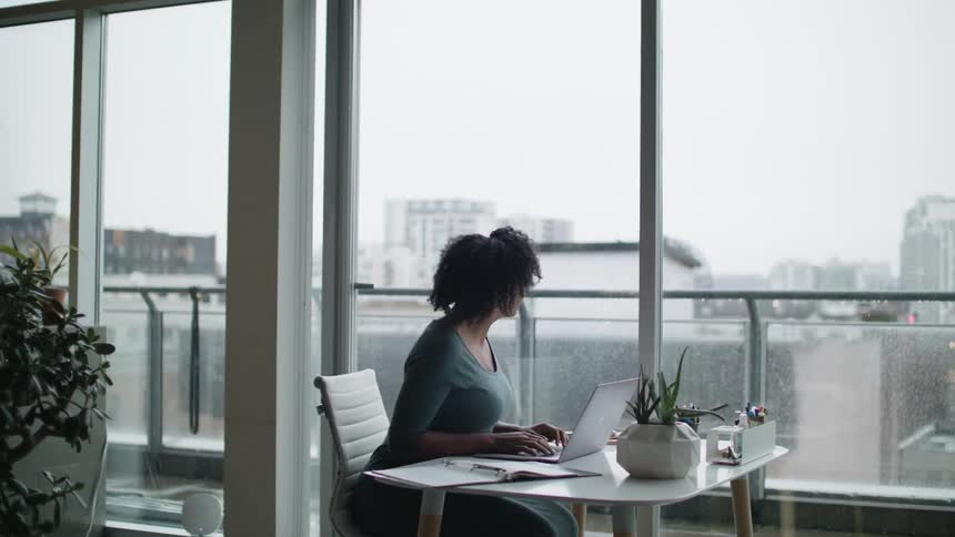 An employee sitting at her desk typing on her laptop