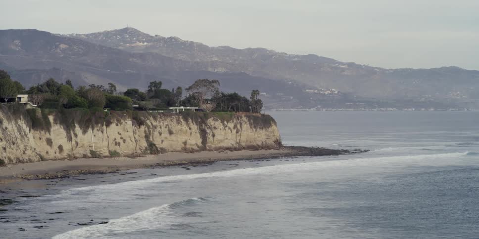 A cliff sits near the shore on a cloudy day